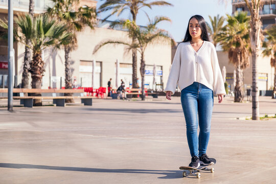 Young Asian Woman Riding A Skateboard In The City