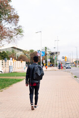 unrecognizable young man walking through the city