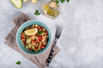  Salmon salad with tomatoes, avocado and quinoa in a blue bowl on a light gray table top view, a dish of balanced diet, copy space for text