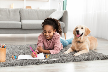 Young afro girl drawing picture with dog at home