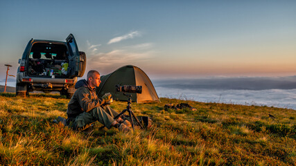 A nature photographer taking photos of mountain sunrise. - obrazy, fototapety, plakaty