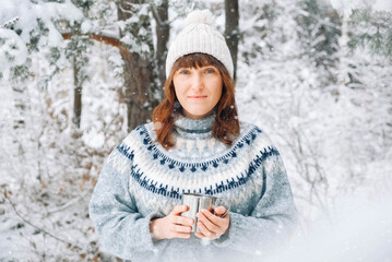 Portrait of a woman with a cup of tea in her hands on a background of snowy forest