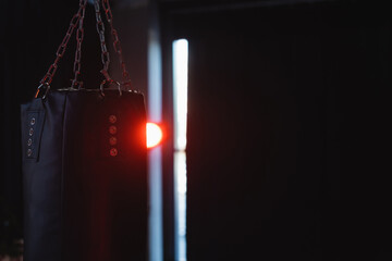 Punching bag on dark background with lighting in gym