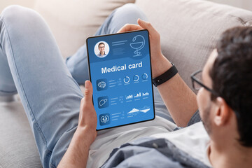 Young man checking his medical card online, using tablet