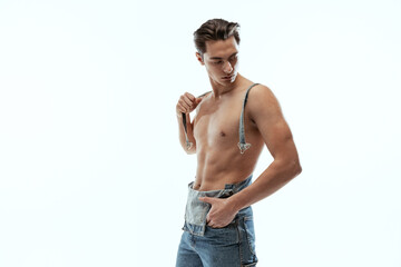 Fototapeta premium Portrait of young handsome sportive shirtless man in jeans posing isolated on white studio background.