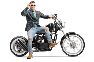 Fototapeta na wymiar Man in stylish suit and jeans sitting on a chopper motorbike and wearing sunglasses