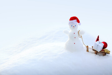 Christmas background with snowman and gifts stand in white snow.