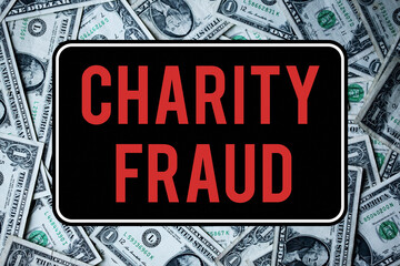 A charity fraud warning sign. In front of dollar bills. Scam and criminal concepts.