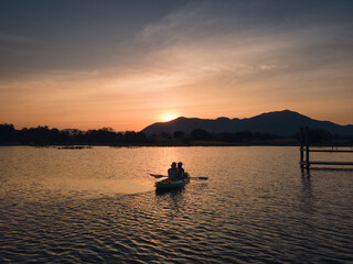 Tourists paddling in canoe on the lake and sunset over mountain