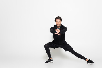 Brunette sportsman looking at camera while training on grey background