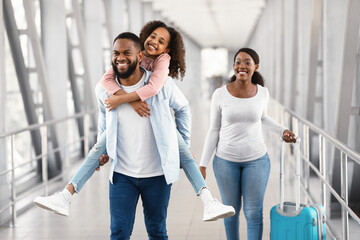 Obraz premium Happy black family traveling with kid, walking in airport