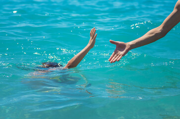 The child is drowning in the water the hand of salvation. Selective focus.