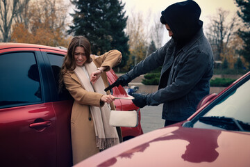 Thief with gun trying to steal woman's bag near car outdoors. Self defense concept