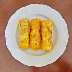 Diples rolls in white plate closeup, traditional Greek gourmet sweet fries with honey syrup and nuts