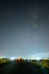 road to the city forest in the night . Night landscape. Nightsky and clouds . Stars in the sky . Lights of the city . 
