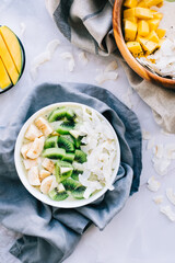 Healthy fruit smoothie bowls on the table with mango, coconut chips and kiwi, healthy nutrition concept.