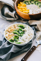 Healthy fruit smoothie bowls on the table with mango, coconut chips and kiwi, healthy nutrition concept.