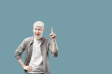 Great idea. Excited albino man pointing finger up, having aha moment over turquoise background with...