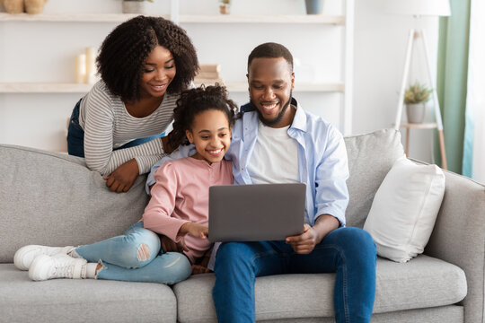 Happy black family using laptop in living room