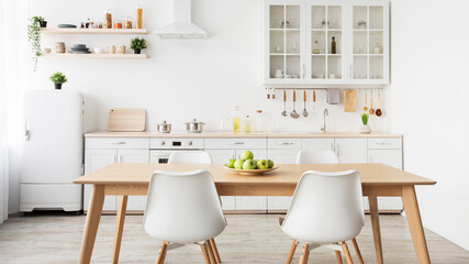 Minimalist design of kitchen. Plate of apples on table, kitchenware and utensils on furniture, panorama