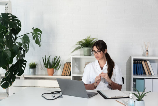 Woman Doctor Reading Email She Received From A Patient Who Thanks Her For Help And Informs Her That He Has Recovered. Female Health Care Medical Worker Using Laptop Computer For Communication.