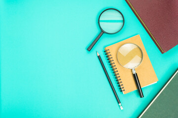 Two magnifying glasses with notebook, pencil, and books with copy space