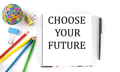 Notebook ,pencils,pen and rubber band with text CHOOSE YOUR FUTURE on the white background