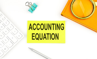 Sticker with the text ACCOUNTING EQUATION on white background, near calculator and notebook