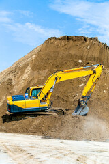 Obraz premium Yellow excavator working digging in sand quarry