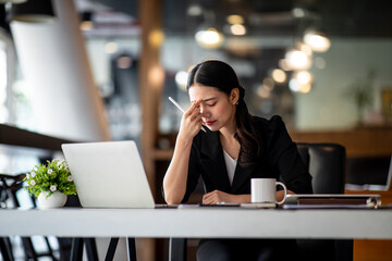 Shot of Asian young businesswoman looking stressed while sitting in her office in front of the...