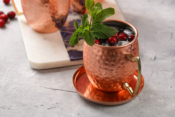 Traditional american alcoholic beverage moscow mule in copper mugs with cranberry and mint on white...