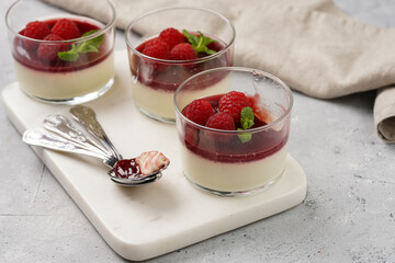 Italian dairy dessert panna cotta with raspberry jam, fresh raspberries and mint on marble board