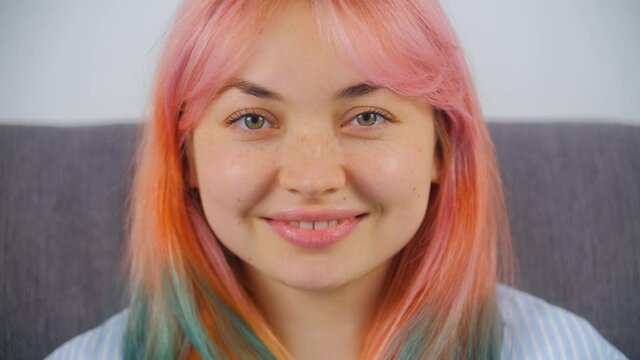 Individual girl with dyed hair smiling in camera. Stock video portrait of cute young woman in late 20s with colored hair