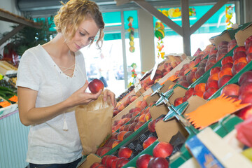female custoemr choosing nectarines in grocers shop