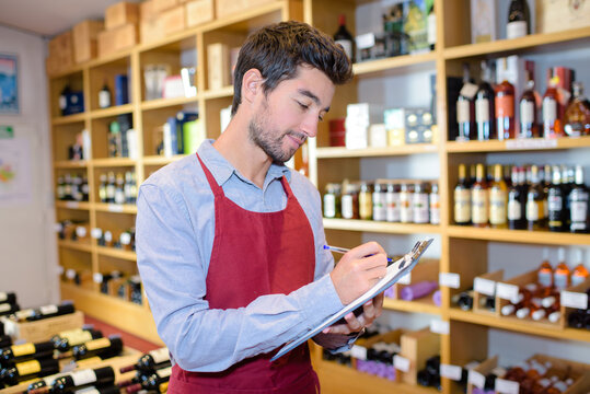 confident male winemaker taking notes on clipboard