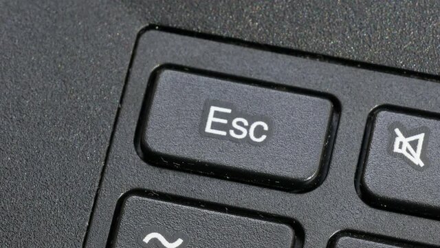 Man pressing the esc escape key on a laptop computer keyboard, finger, macro, detail, extreme closeup. Stopping, ceasing, escape sequence, quitting, cancelling an action abstract concept, technology