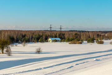 Winter panoramic view landscape with small house, snowy meadow, forest in background in Northern Europa