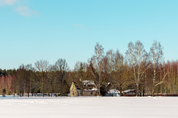 Winter panoramic view landscape with small house, snowy meadow, forest in background in Northern Europa