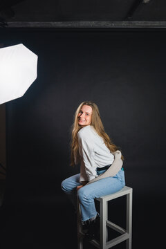 Cheerful female sitting on chair in photo studio