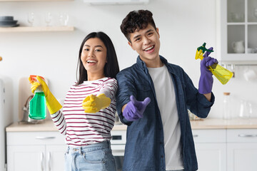 Cheerful asian house-keepers posing while cleaning kitchen