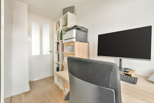 Working table with modern computer near bookshelf