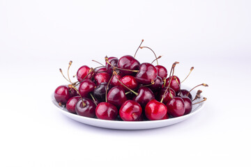 Sweet red cherry on white ceramic plate on white background.