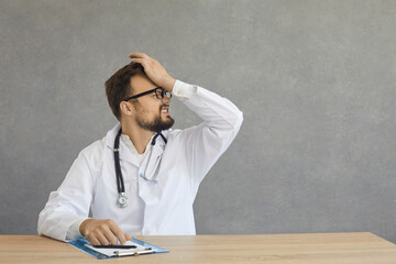 Caucasian adult disappointed overworked doctor in white coat feeling shame surprise showing stress...
