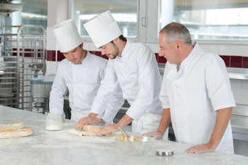 chief chef watching his assistants making a dough