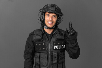 SWAT caucasian man isolated on grey background showing and lifting a finger in sign of the best