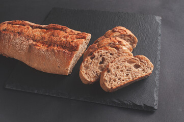 Fresh crispy French baguette on a black stone background.