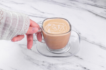 Woman hands holding Cup of coffee on marble texture background.