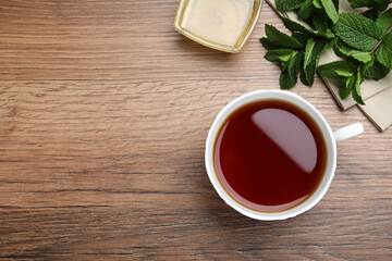 Cup of hot aromatic tea with mint and honey on wooden table, flat lay. Space for text