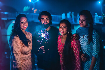 Three young Indian women and a men with bengal fireworks, celebrating. Indian Festival Diwali. New...