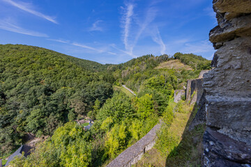 Fototapeta na wymiar Countryside with mountains covered with lush green trees with a blue sky in the background, seen from the ruined fortress with stone walls of Brandenbourg Castle, sunny summer day in Luxembourg